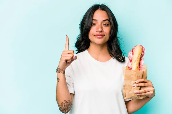 Young Hispanic Woman Eating Sandwich Isolated Blue Background Showing Number — Stockfoto