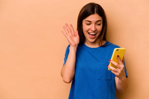 Joven Mujer Caucásica Sosteniendo Teléfono Móvil Aislado Sobre Fondo Beige —  Fotos de Stock