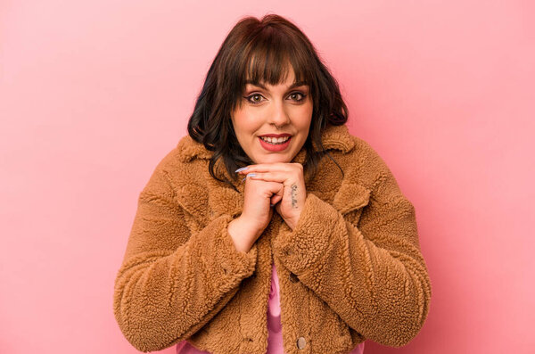 Young caucasian woman isolated on pink background praying for luck, amazed and opening mouth looking to front.