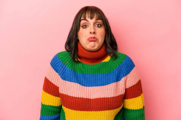 Pembe arka planda soyutlanmış beyaz bir kadın omuzlarını silkeliyor ve gözleri açık..