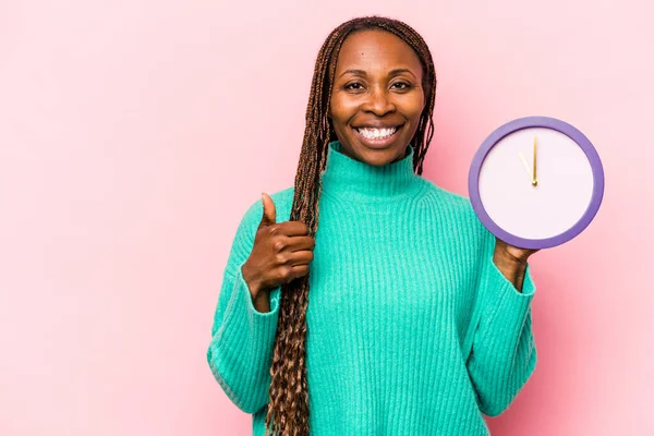 Ung Afroamerikansk Kvinna Håller Klocka Isolerad Rosa Bakgrund Ler Och — Stockfoto