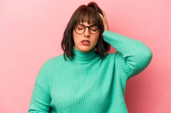 Pembe arka planda izole edilmiş genç beyaz kadın yorgun ve uykulu ellerini başının üstünde tutuyor..