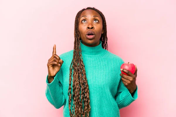 Ung Afroamerikansk Kvinna Håller Ett Äpple Isolerad Rosa Bakgrund Pekar — Stockfoto