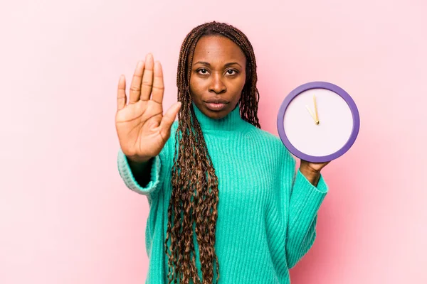 Молодая Афроамериканка Держащая Часы Изолированные Розовом Фоне Стоящие Протянутой Рукой — стоковое фото