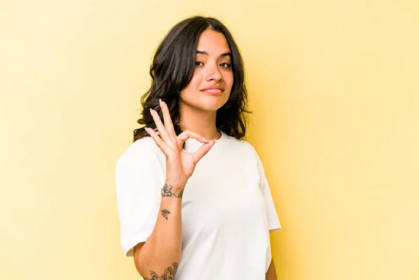 Young Hispanic Woman Isolated Yellow Background Winks Eye Holds Okay — 스톡 사진