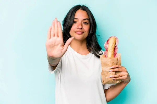 Young Hispanic Woman Eating Sandwich Isolated Blue Background Standing Outstretched — Stockfoto