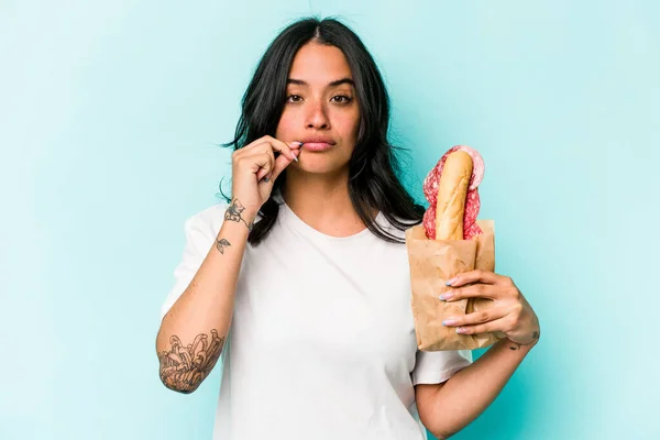 Young Hispanic Woman Eating Sandwich Isolated Blue Background Fingers Lips — Stockfoto