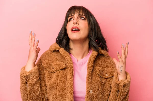 Pembe arka planda izole edilmiş genç beyaz kadın gökyüzüne haykırıyor, yukarı bakıyor, hayal kırıklığına uğramış..