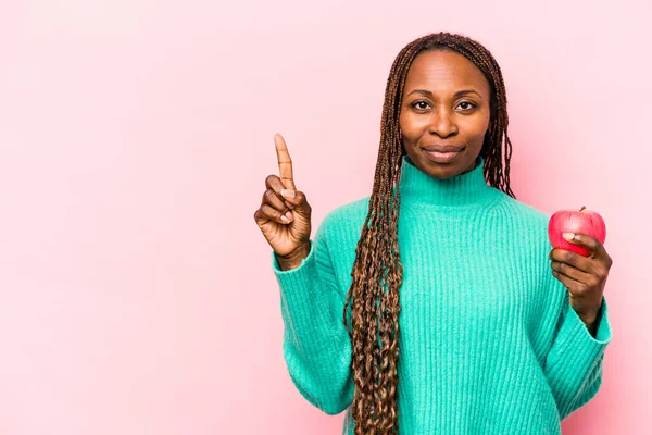 Ung Afroamerikansk Kvinna Håller Ett Äpple Isolerat Rosa Bakgrund Visar — Stockfoto