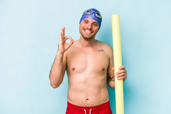 Young Caucasian Swimmer Man Holding Foam Stick Isolated Blue Background — 스톡 사진