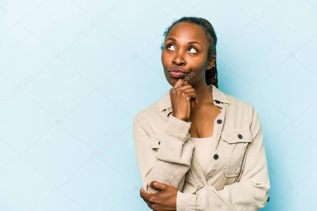 Young african american woman isolated on blue background relaxed thinking about something looking at a copy space.