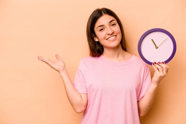 Elinde bej arka planda izole edilmiş bir saat tutan genç İspanyol kadın bir avuç içinin fotokopisini çekiyor ve başka bir elini belinde tutuyor..