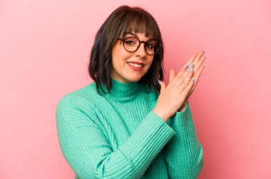 Pembe arka planda soyutlanmış genç beyaz kadın enerjik ve rahat hissediyor, ellerini ovuşturuyor..