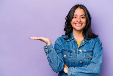 Mor arka planda izole edilmiş genç İspanyol kadın bir avuç içinde fotokopi alanı ve belinde bir el daha gösteriyor..