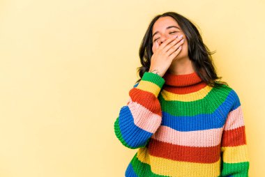 Sarı arka planda izole edilmiş genç İspanyol kadın gülüyor, kaygısız, doğal duygu..