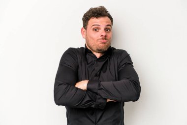 Beyaz arka planda izole edilmiş genç beyaz bir adam omuz silkiyor ve gözleri açık..