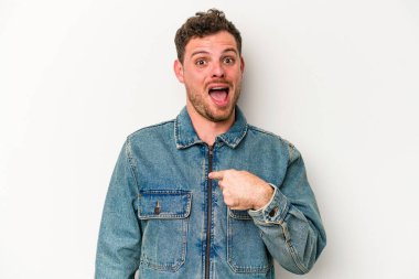 Beyaz arka planda izole edilmiş genç beyaz bir adam parmağını göstererek şaşırdı, geniş bir gülümsemeyle..