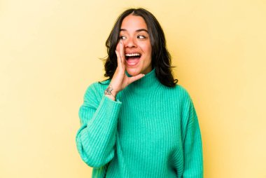 Sarı arka planda izole edilmiş genç İspanyol kadın heyecanla bağırıyor..