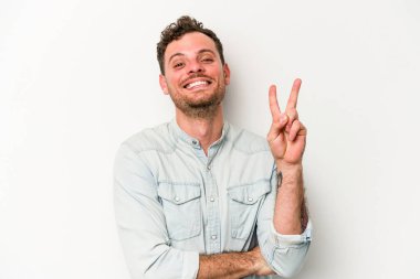 Beyaz arka planda izole edilmiş genç beyaz adam iki numarayı parmaklarıyla gösteriyor..