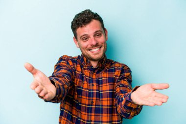 Mavi arka planda izole edilmiş beyaz bir genç hoş bir yüz ifadesi sergiliyor..