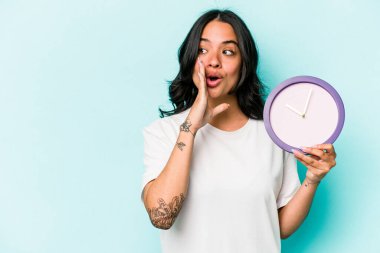 Mavi arka planda izole bir saat tutan genç İspanyol kadın gizli bir sıcak fren haberi söylüyor ve yana bakıyor