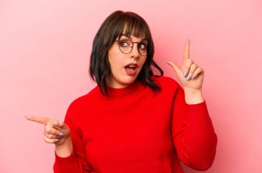 Pembe arka planda izole edilmiş genç beyaz kadın farklı kopya alanlarını gösteriyor, birini seçiyor, parmağıyla gösteriyor..