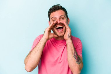 Kafkasyalı genç adam mavi arka planda izole edilmiş. Dedikodu yapıyor, bir şeyleri bildiriyor..