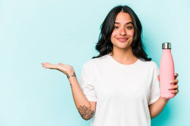 Mavi arka planda termo tutan genç İspanyol kadın bir avuç içinde fotokopi alanı ve belinde bir el daha gösteriyor..