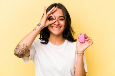 Pembe arka planda izole edilmiş anahtar taşıyan İspanyol bir kadın heyecanlı..