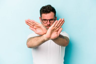 Kafkasyalı genç adam mavi arka planda izole edilmiş bir şekilde inkar hareketi yapıyor.