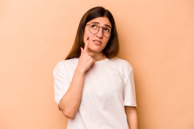 Genç İspanyol kadın bej arka planda izole edilmiş ağlayan, bir şeyden mutsuz, acı ve kafa karışıklığı olan.