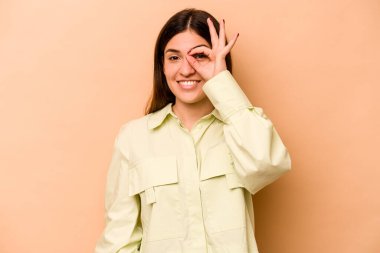 Latin kökenli genç bir kadın, bej arka planda izole edilmiş. Heyecanlı..