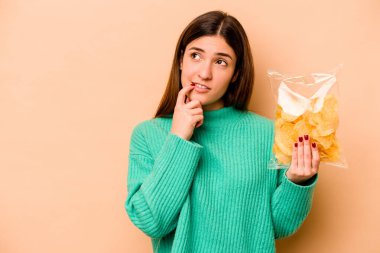 Latin kökenli genç bir kadın, elinde bej arka planda izole edilmiş bir çanta tutuyor. Bir şeyin fotokopi odasına baktığını düşünüyor..
