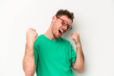 Beyaz arka planda izole edilmiş genç beyaz adam tasasız ve heyecanlı bir şekilde tezahürat yapıyor. Zafer konsepti.