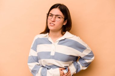 Genç İspanyol kadın bej arka planda izole edilmiş karaciğer ağrısı, mide ağrısı var..