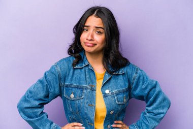 Mor arka planda izole edilmiş genç İspanyol kadın kafası karışmış, şüpheli ve güvensiz hissediyor..