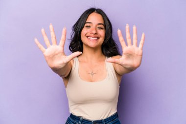 Mor arka planda izole edilmiş genç İspanyol kadın on numarayı elleriyle gösteriyor..