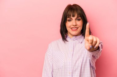 Pembe arka planda izole edilmiş beyaz bir kadın bir numarayı parmağıyla gösteriyor..