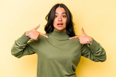 Sarı arka planda izole edilmiş genç İspanyol kadın parmakları aşağıda, olumlu bir his var..