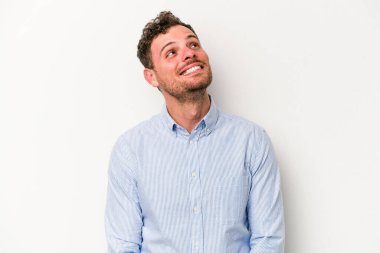 Beyaz arka planda izole edilmiş genç beyaz adam gevşemiş ve mutlu bir şekilde gülüyor, boynunda dişlerini gösteriyor..