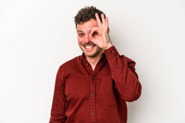 Beyaz arka planda izole genç beyaz adam heyecanlı tamam göz jesti tutmak.