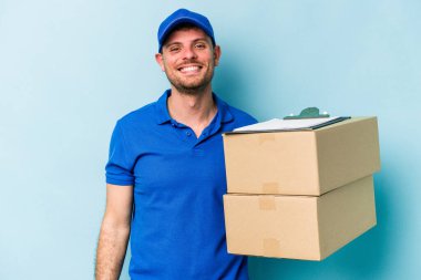 Kafkasyalı genç teslimatçı mavi arka planda izole edilmiş mutlu, güler yüzlü ve neşeli.