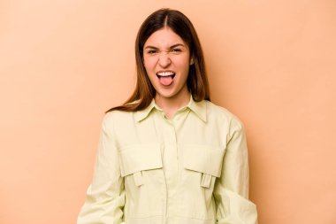 Genç İspanyol kadın bej arka planda izole edildi. Komik ve dost canlısı bir dil uzattı..
