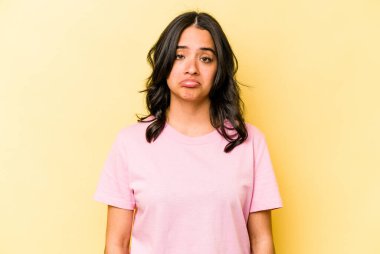 Genç İspanyol kadın sarı arka planda izole edilmiş üzgün, ciddi yüzlü, mutsuz ve hoşnutsuz..