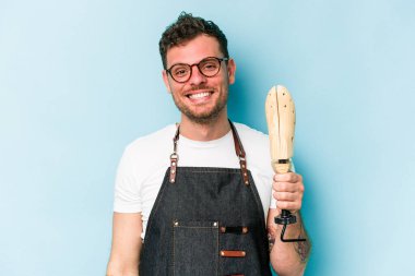 Kafkasyalı genç kunduracı mavi arka planda izole edilmiş mutlu, güler yüzlü ve neşeli..