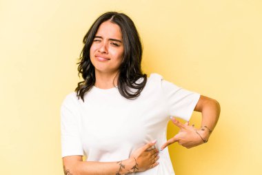 Sarı arka planda karaciğer ağrısı çeken, karnı ağrıyan genç bir İspanyol kadın..