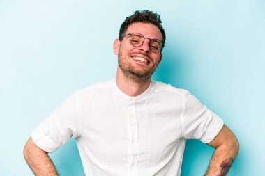 Mavi arka planda izole edilmiş genç beyaz adam mutlu, güler yüzlü ve neşeli.