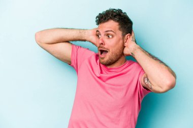 Genç beyaz adam mavi arka planda izole edilmiş bağırıyor, çok heyecanlı, tutkulu, bir şeyden memnun..