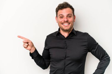 Beyaz arka planda izole edilmiş genç beyaz adam işaret parmağıyla işaret ederek gülümsüyor..