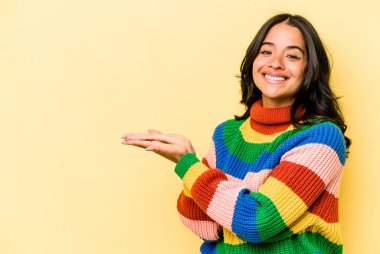 Sarı arka planda izole edilmiş genç İspanyol bir kadın. Elinde palmiyesinde bir kopya alanı var..